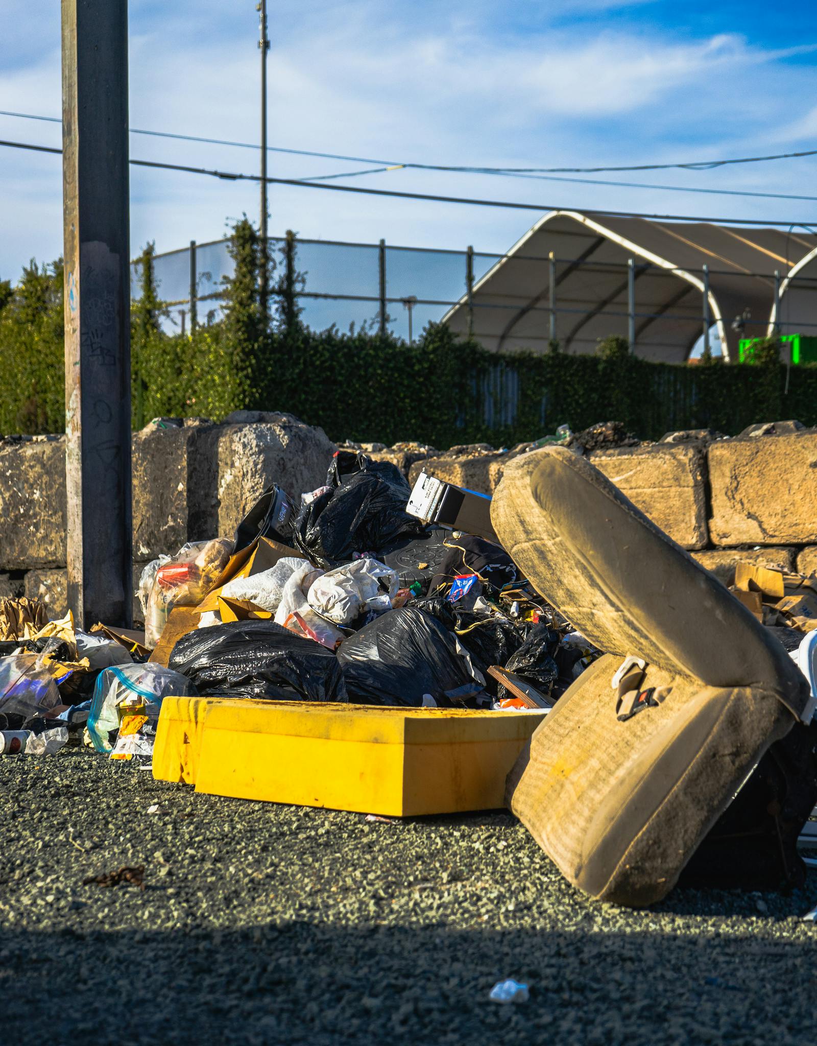 Outdoor scene of a garbage pile including a discarded mattress and various waste materials.